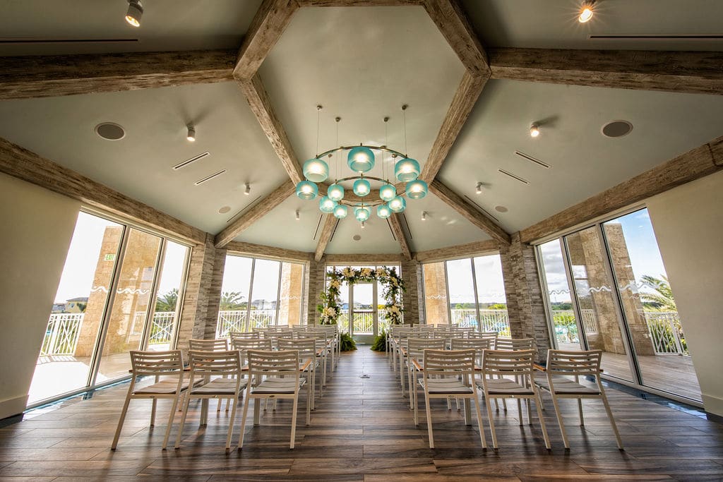 indoor wedding ceremony set up in modern tropical room with wood rafters and sea green light fixtures - margaritaville resort orlando